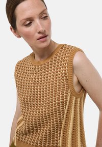 Haut sans manches en tricot marron, présentant un motif texturé avec un col côtelé et des détails de rayures plus claires sur les côtés.