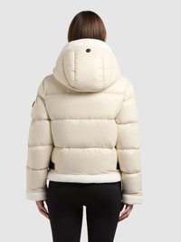 Kołnierz i mankiety z miękkiego białego polaru, pikowana, kość słoniowa kurtka puchowa. Posiada teksturę pikowaną, okrągły kaptur oraz czarny ozdobny guzik.
