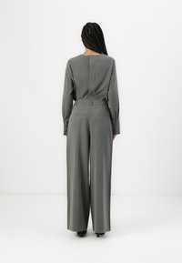 Grå pinstripesuit som har en langermet topp og vide bukser, med en skreddersydd passform og subtil tekstur, vist fra baksiden.