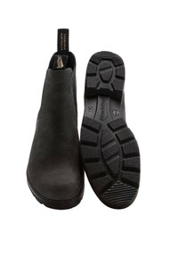 Zwarte leren enkelboots met een gladde afwerking, elastische zijpanelen en een robuuste rubberen zool met een getailleerd ontwerp voor grip.