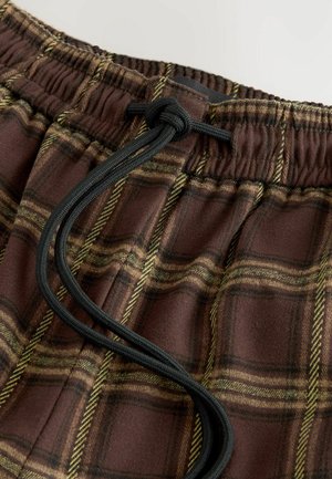 Bruneternede plaid-loungebukser med gule og grønne striber, med elastisk talje og sort snøre til justering. Blød stoftekstur.