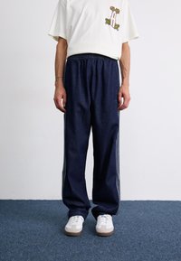 Denim jogger pants in dark blue with a relaxed fit, featuring a tapered shape, elastic waistband, and contrasting side stripes.