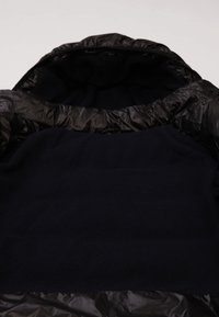 Černá prošívaná bunda s kapucí; hladký, lesklý povrch na vnější straně a měkký pletený vnitřek. Hlavní barva je tmavě námořnická modř.