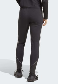 Zwarte sportbroek met een strakke pasvorm, voorzien van witte zijstrepen, een elastische tailleband en een gladde, lichte stof.