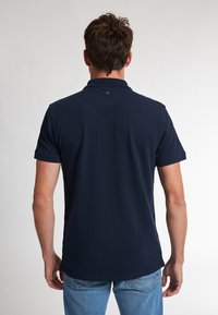 Námořnická modrá polo tričko s krátkým rukávem, vyrobené z bavlny, s klasickým límcem a malým logem na zadním výstřihu.