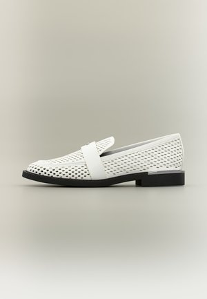 Mocassin en cuir blanc perforé avec semelle noire, talon bas et large bride sur le dessus, présenté en profil sur fond neutre.