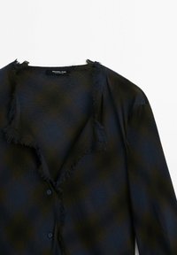 Veste à carreaux noire et vert foncé avec bords effilochés et deux boutons, étiquetée Massimo Dutti, posée à plat sur fond blanc.
