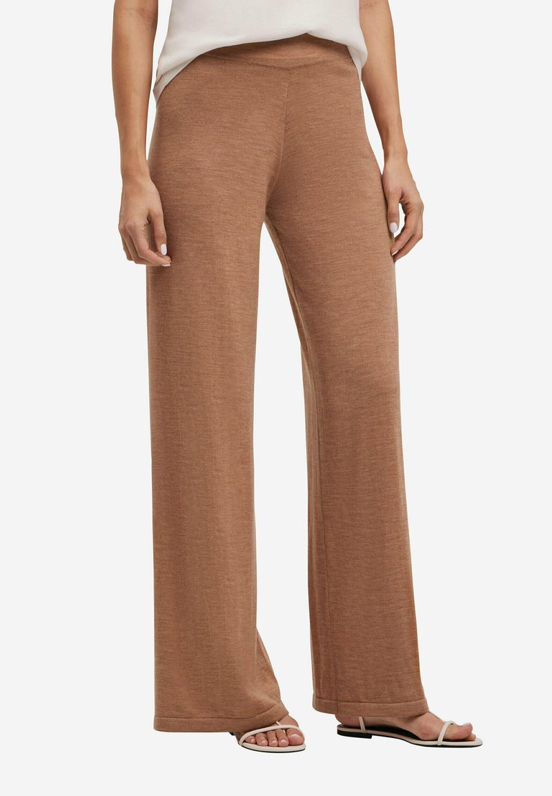 Bruine wijde broek van zacht, textuurstof, met een hoge taille en een ontspannen pasvorm, gecombineerd met minimalistische platte sandalen.