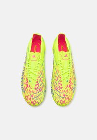 Botas de fútbol amarillo neón con una parte superior texturizada, diseño de estampado de leopardo en rosa y púrpura, y un acolchado interior de color rosa brillante en contraste.