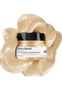 Hårmaskebeholdere med kremet, beige produkt. Svart lokk med hvitt merke som beskriver "Absolut Repair" og bruk for tørt, skadet hår. 250 ml størrelse.