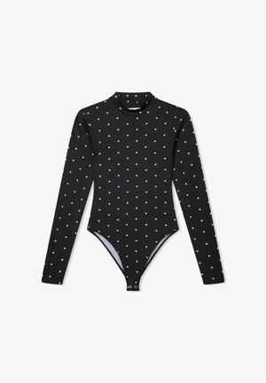 Body nero a maniche lunghe con pois bianchi, colletto alto e chiusura a pressione sul fondo. Realizzato in tessuto elasticizzato per un aspetto aderente.
