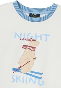 Camiseta de algodón blanca con cuello a rayas azules y un diseño impreso de un oso esquiador que lleva una bufanda roja y blanca. Texto: "ESQUÍ NOCTURNO."