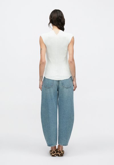 Λευκό αμάνικο τοπ με υφασμάτινη ριμπ υφή, συνδυασμένο με άνετο ανοιχτό μπλε τζιν παντελόνι και παπούτσια με animal print.