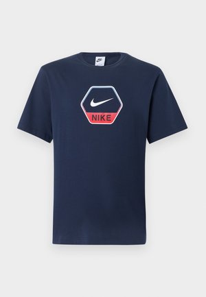 Μπλε ναυτικό T-shirt Nike με κοντά μανίκια, στρογγυλή λαιμόκοψη και εξαγωνικό λογότυπο με λευκή γραμμή Swoosh και κόκκινο κείμενο "NIKE" στο μπροστινό μέρος.