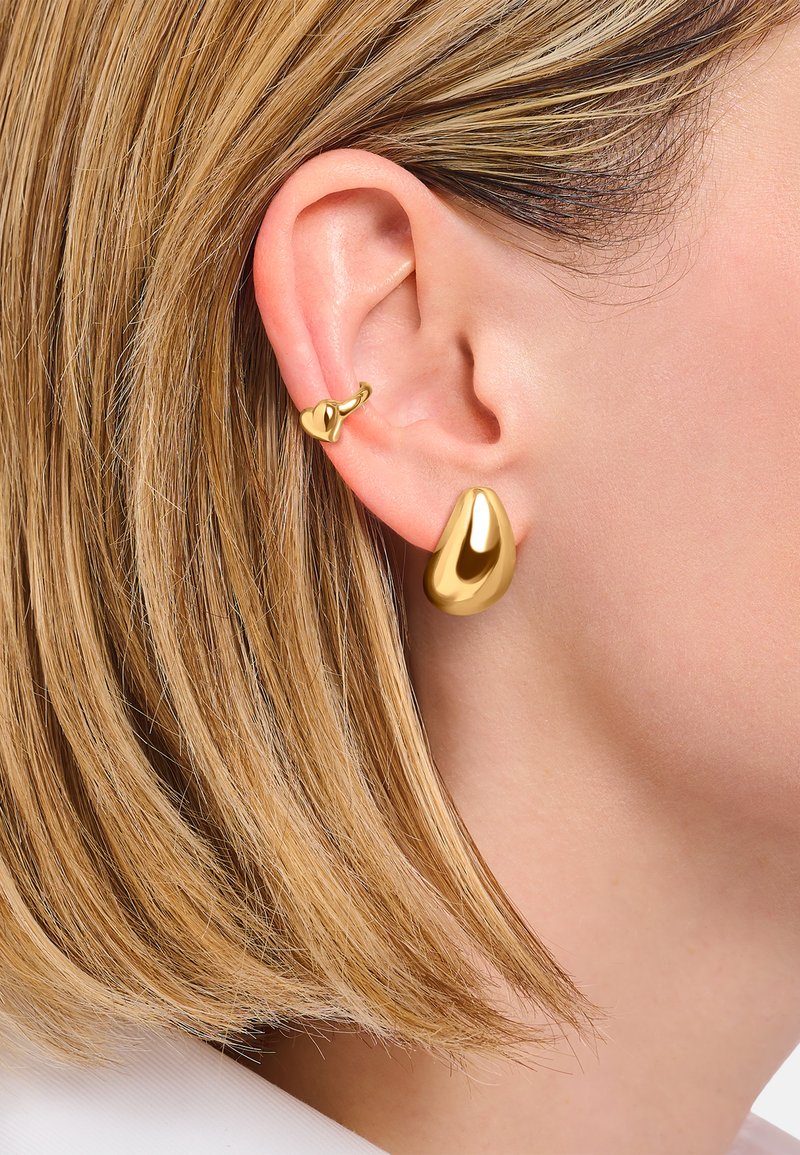 Goldfarbene Tropfohrringe mit einer Träneform, die eine glatte, reflektierende Oberfläche aufweisen; begleitet von einem kleinen goldenen Creolenohrring.