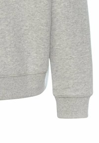 Grijze hoodie van een gestructureerde stof, met ribgebreide boorden en zoom, en een ontspannen pasvorm. Close-up van de onderste mouw en tailleband detail.