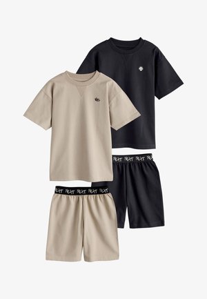 Dos juegos de camisetas de manga corta y pantalones cortos, uno beige con el logo "NYC", uno negro con el logo de una calavera, ambos con cinturillas elásticas etiquetadas con "Next."