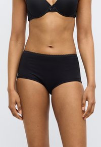 Μαύρο βαμβακερό εσώρουχο τύπου hipster με ελαστική μέση με κυματιστό τελείωμα. Λείο υλικό και εφαρμοστή γραμμή, που τελειώνει πάνω από τη μέση του μηρού.