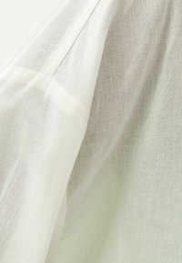 White, lightweight fabric with a slightly textured surface. Features a smooth seam along the edge, suggesting a soft drape.