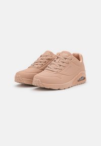 Sko i blushfärgad nyans med en slät syntetisk ovandel, snörning, luftiga perforeringar och synlig luftdämpning i sulan.