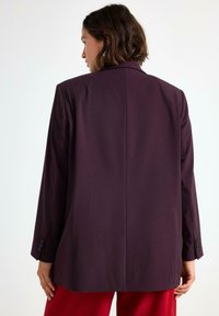 Burgundy blazer med en skräddarsydd passform, med långa ärmar, en enda bakre slits och knäppning vid ärmsluten, tillverkad av ett slätt tyg.