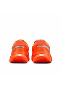 Un paio di scarpe da corsa arancioni brillanti viste da dietro, con strisce riflettenti argentate e suole strutturate su uno sfondo bianco.