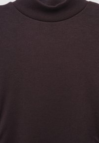 Dunkelbrauner Strickstoff in Nahaufnahme mit sichtbarer Textur und einem sanft gefalteten Rollkragen.