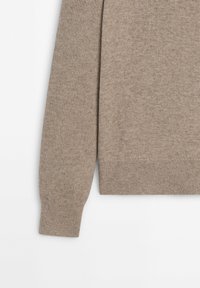 Pull beige à manches longues en maille avec poignets et ourlet côtelés, présenté sur un fond blanc, montrant les détails des manches et du torse.