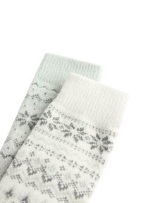 Dve pleteni volneni nogavički s sivimi in belimi nordijskimi vzorci, rebrastimi manšetami in z geometričnimi vzorci s temo zime.