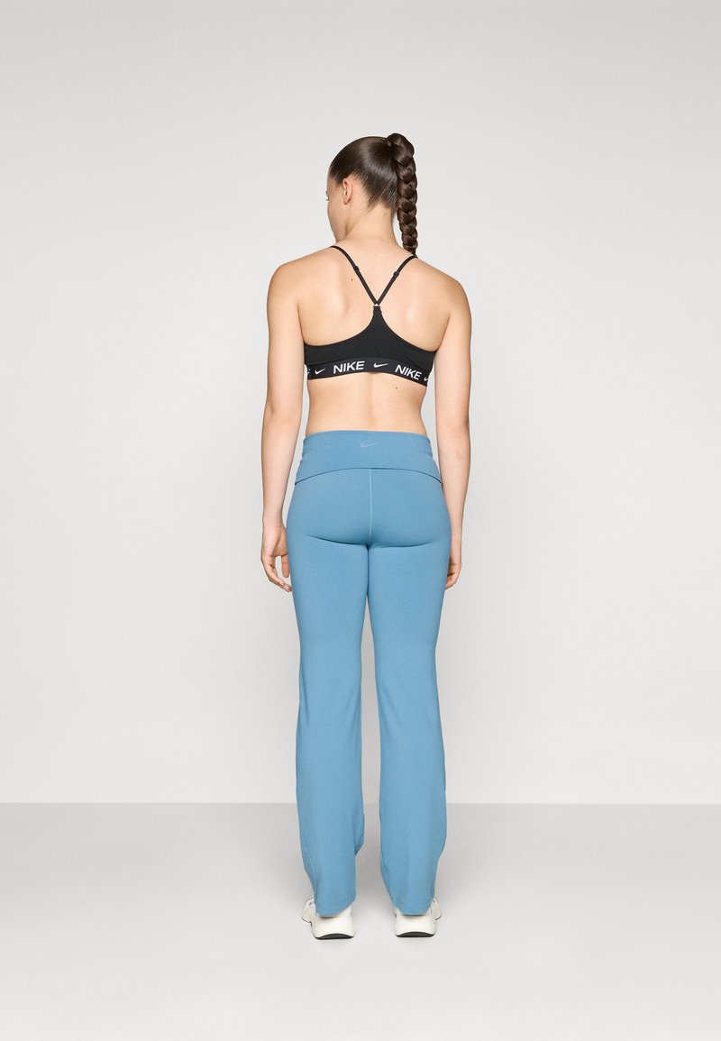 Top sportivo nero con spalline regolabili, abbinato a pantaloni da allenamento azzurri chiari a forma svasata con vita aderente e logo Nike sulla vita.