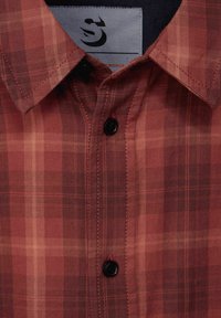 Červená a hnědá kostkovaná košile s límečkem na knoflíky, s černými knoflíky a kontrastním šitím. Visačka viditelná na límci.