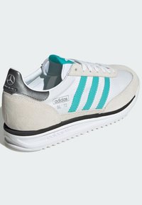 Adidas SL '72 tenisice imaju bijelo kožno tijelo, tirkizne pruge, sivi nubuk na peti i teksturiranu crnu gumenu potplatu.