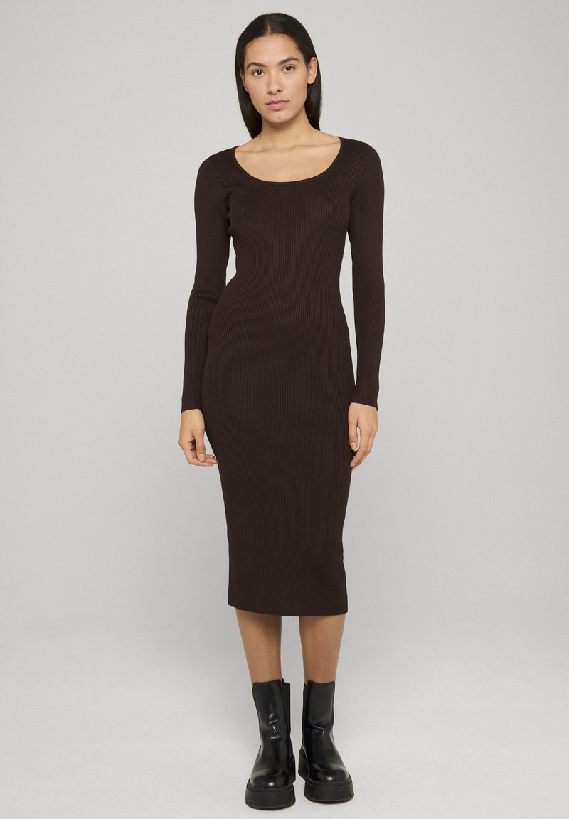 Robe marron côtelée à manches longues, col en U, silhouette ajustée et longueur mi-mollet, associée à des bottines noires.