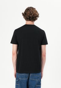 Sort bomulds T-shirt med rund hals og korte ærmer, vist fra bagsiden. Har en glat overflade og en tætsiddende pasform.
