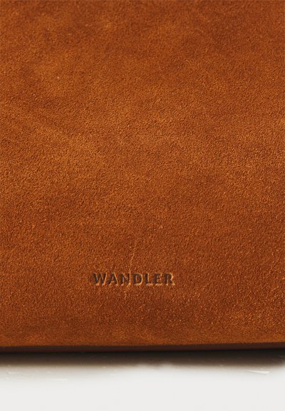 Pehme ja tekstureeritud pruuni suede materjal koos embosseeritud "WANDLER" logoga. Pind on ühtlane, kus on kergeid variatsioone varjundis.