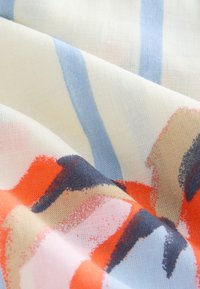 Tissu léger et transparent avec des rayures verticales bleues et des motifs abstraits de coups de pinceau orange, beige, noir et rose, présenté en plis doux.