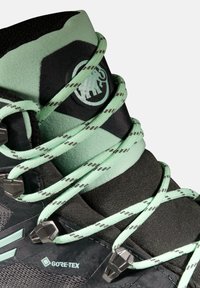 Scarponi da trekking neri e verde menta con collo alto, dotati di tessuto testurizzato, componenti robusti e lacci riflettenti. Visibile il marchio GORE-TEX.