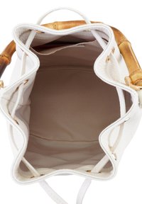 Sac en cuir blanc avec une anse en bambou, ouvert sur le dessus, et doublure en tissu doux, présentant un extérieur texturé et des accents en métal doré.