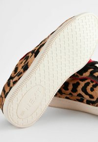 Sneaker con stampa leopardata, upper in pelliccia testurizzata, accenti rossi a contrasto e suola in gomma bianca con battistrada decorato per una migliore aderenza.