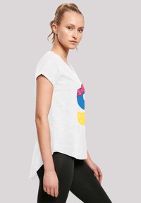 Balta trumpa rankovė t-shirt marška, kurią puošia spalvingas piešinys su mėlynu apskritimu, rožine lanku ir geltonais elementais. Laisvas siluetas, minkšta medžiaga.
