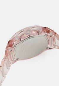 Klart pink plastikkwatch med et rundt urkasse, gennemsigtig rem, polerede sølvdetaljer og tre trykknapper på højre side.