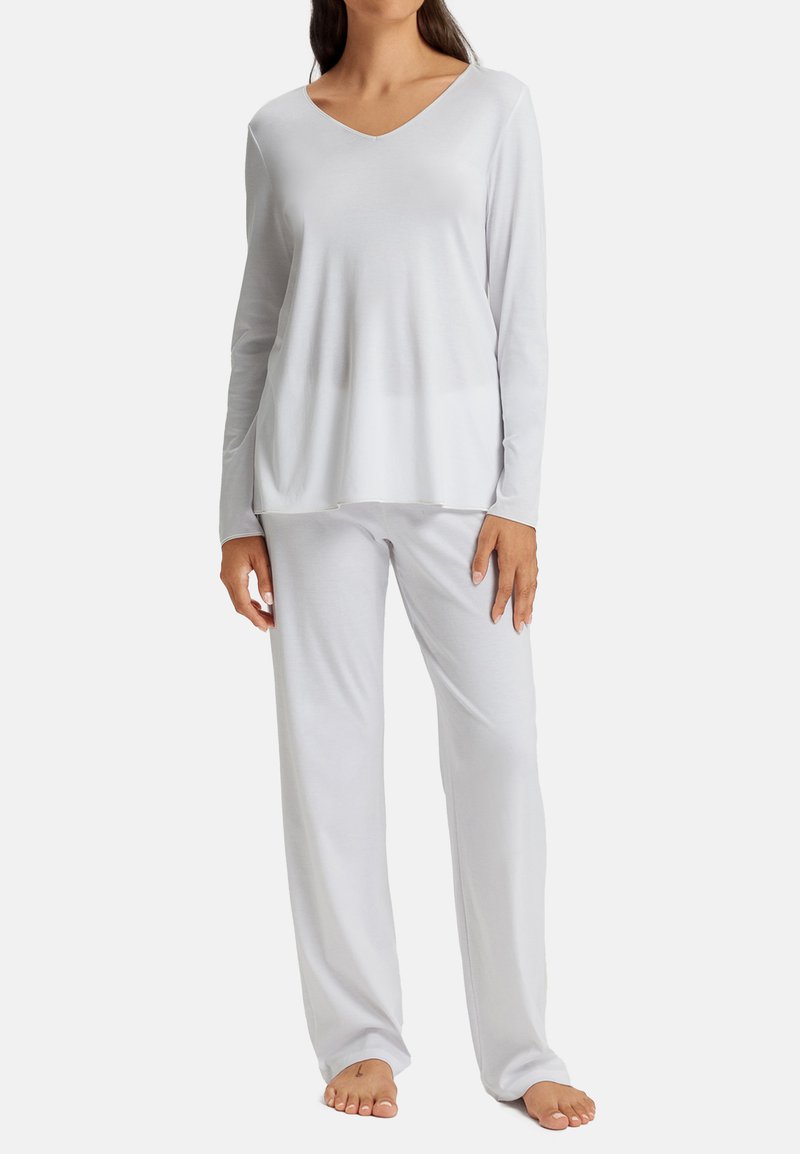 Top bianco a maniche lunghe con scollatura a V, abbinato a pantaloni da pigiama larghi dello stesso colore. Tessuto morbido e liscio con un design minimalista.