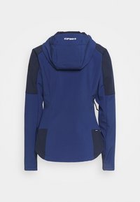 Veste technique bleue avec capuche, présentant des accents bleu foncé, une coupe ajustée et une texture de tissu lisse. Comprend deux poches latérales.