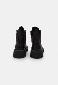 Botas negras de cuero hasta el tobillo con laterales texturizados, cierres de cremallera y suelas de goma gruesas, que cuentan con un tacón apilado para mayor estabilidad.