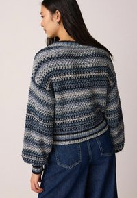 Pull en maille avec un motif de rayures horizontales dans des tons de bleu et de crème, avec une coupe courte et des manches bouffantes.