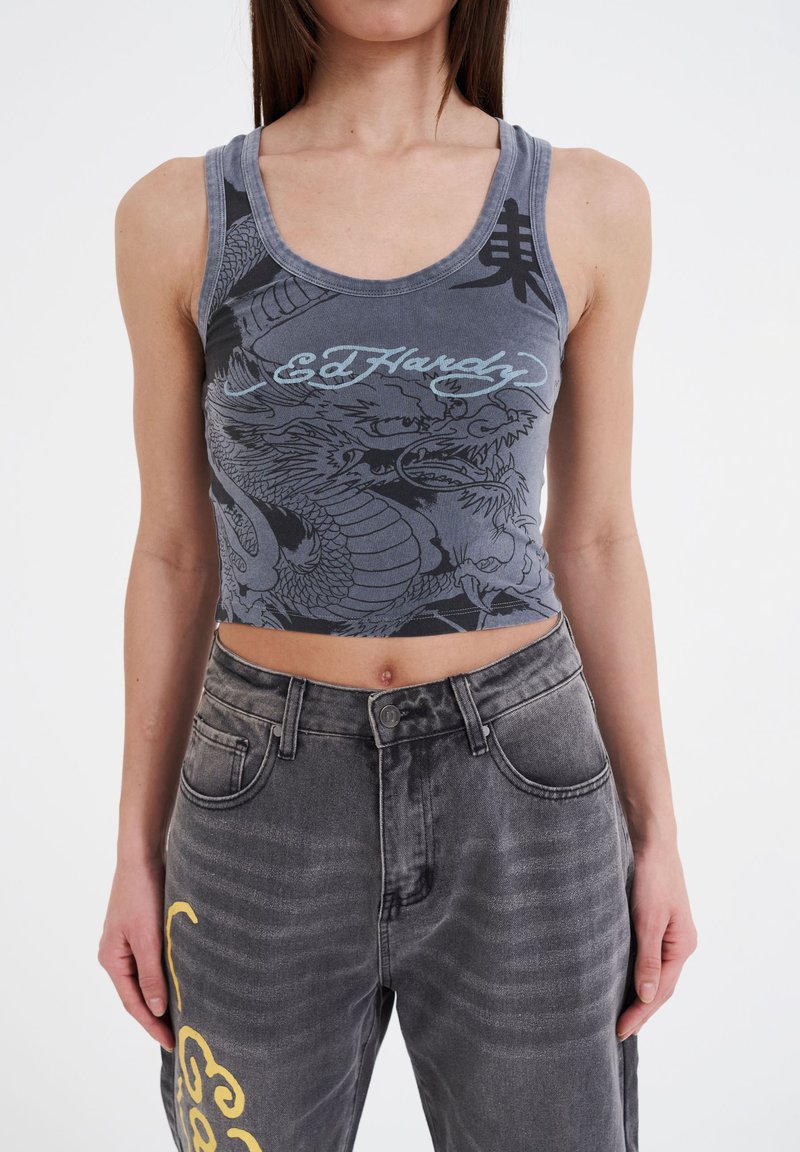 Gray cropped tank top with dragon graphic and blue lettering, paired with gray denim pants featuring yellow accent, textured surface and pockets.