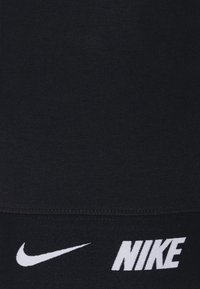 Svarta atletiska leggings med texturerad finish, försedda med vita Nike-logotypen och swoosh-accenter nära fållen. Flexibelt material för komfort.