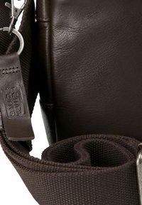 Bolso de hombro de cuero marrón con superficie texturizada, que cuenta con una correa de tela desmontable y acentos de metal.