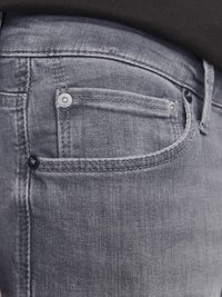 Graue Jeans aus Denim mit glatter Textur, ausgestattet mit einer kleinen Vordertasche, metallischen Beschlägen und einer Nahaufnahme der Naht am Bund.