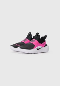 Béquilles noires et roses à enfiler avec des semelles blanches, swoosh Nike noir et texte "JUST DO IT" sur la sangle rose.